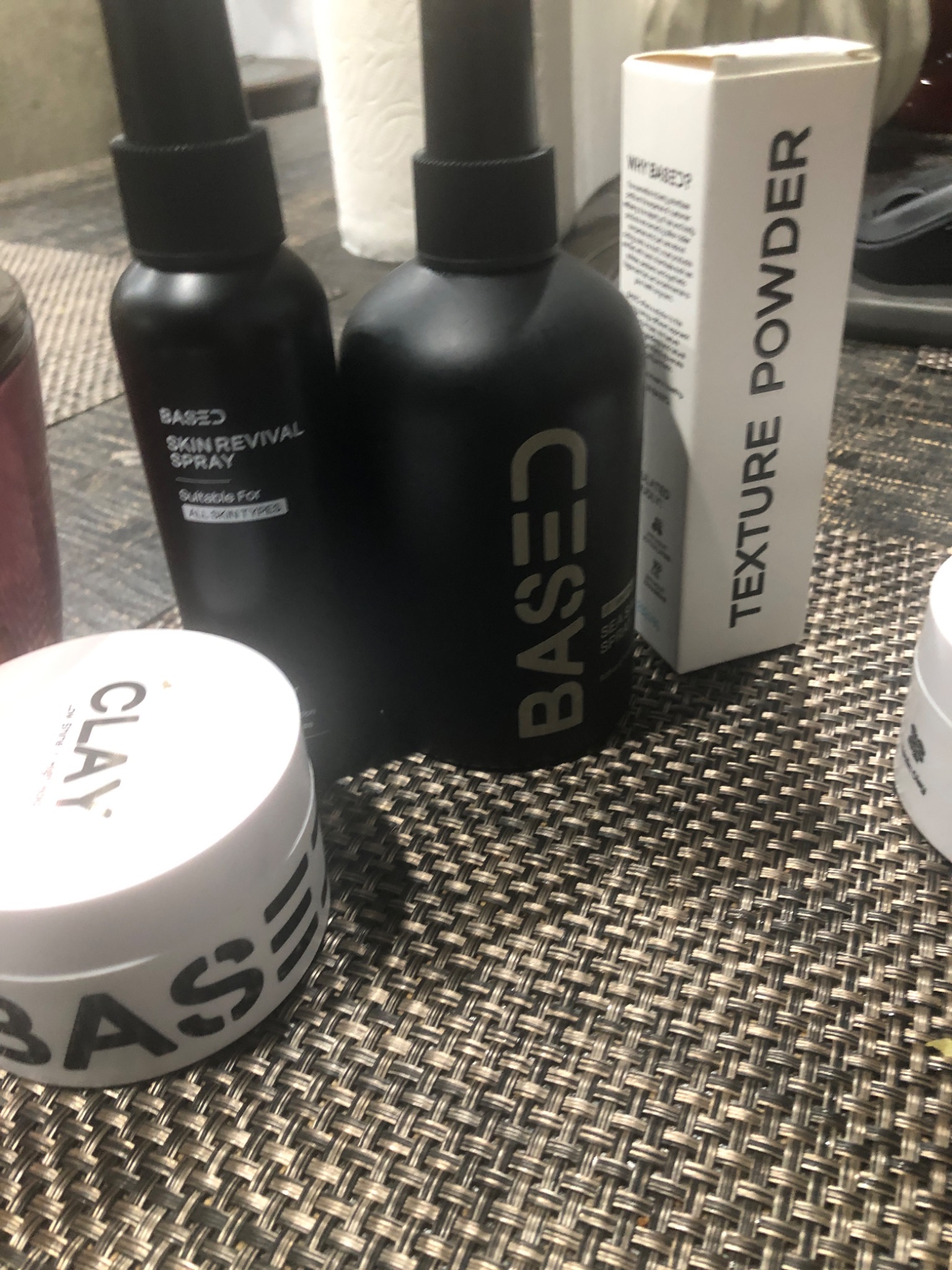 Grooming products including a jar of BASED Hair Clay photographed at home.